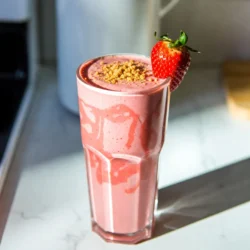 To make the Strawberry Cheesecake Smoothie, you will need: - 1 cup fresh strawberries, hulled and halved - 1/2 cup cream cheese, softened - 1/2 cup Greek yogurt - 1/2 cup milk (dairy or non-dairy) - 2 tablespoons honey or agave syrup (adjust to taste) - 1 teaspoon vanilla extract - 1/4 cup graham cracker crumbs (plus extra for garnish) - Ice cubes (optional, for a thicker smoothie) You can easily swap some ingredients if needed: - Use low-fat cream cheese for a lighter option. - Replace Greek yogurt with regular yogurt or a plant-based yogurt. - Almond milk or oat milk works well instead of regular milk. - Maple syrup can replace honey for a vegan choice. - For a gluten-free option, use gluten-free graham crackers. Each serving of this smoothie offers a delightful mix of flavors and nutrients: - Calories: 280 - Protein: 10g - Carbohydrates: 36g - Fat: 10g - Fiber: 2g - Sugar: 20g This smoothie is not just tasty; it's also a good source of protein and vitamins. Enjoy a delicious treat that feels like dessert but keeps you satisfied! {{ingredient_image_1}} First, gather your ingredients. You will need fresh strawberries, cream cheese, Greek yogurt, milk, honey, vanilla extract, graham cracker crumbs, and ice cubes. Start by hulling and halving the strawberries. This helps them blend easily. Make sure the cream cheese is softened. This makes mixing smooth and easy. Now, place the strawberries, cream cheese, Greek yogurt, and milk in a blender. Add the honey or agave syrup and vanilla extract. If you like a thicker smoothie, toss in some ice cubes. Blend everything on high speed until it is smooth and creamy. Sometimes, you might need to scrape down the sides. This helps mix in any bits that stick. After blending, add the graham cracker crumbs. Pulse a few times to mix them in without fully blending. Taste the smoothie. If it needs more sweetness, add more honey or syrup. Pour the smoothie into tall glasses. For a fun touch, sprinkle extra graham cracker crumbs on top. You can also add a fresh strawberry on the rim of the glass. Serve with a straw for a delightful drink! To get the best texture, use fresh strawberries. They blend smoothly and offer great flavor. If you want a thicker smoothie, add ice cubes. This makes the drink cold and creamy. Blend until itβs smooth but leave some graham cracker bits. This adds a nice crunch. Taste is key when making this smoothie. Start with two tablespoons of honey or agave syrup. Blend and taste the smoothie. If it needs more sweetness, add a little more. Remember, strawberries can vary in sweetness. Adjust to your liking for the best flavor. You can prepare this smoothie ahead of time. Blend all the ingredients except for the graham cracker crumbs. Store it in the fridge for up to a day. When youβre ready to serve, add the crumbs and blend again. This keeps the texture nice and fresh. Pro Tips Fresh Strawberries Matter: Use ripe, fresh strawberries for the best flavor and sweetness in your smoothie. Adjust Sweetness to Your Taste: Depending on the ripeness of your strawberries, you may need to adjust the amount of honey or agave syrup. Chill Your Ingredients: For a colder smoothie, chill your ingredients beforehand or use frozen strawberries. Graham Cracker Texture: For added texture, use a mix of fine and chunky graham cracker crumbs when adding to the smoothie. {{image_2}} To make a dairy-free version, swap the cream cheese and yogurt for non-dairy options. Use cashew cream or coconut cream in place of cream cheese. For yogurt, try coconut yogurt or almond yogurt. Use almond milk or oat milk instead of regular milk. This way, you can enjoy the same rich flavor without dairy. You can mix in different fruits for a new twist. Try banana or blueberries for a fruity touch. Adding a tablespoon of peanut butter gives a nutty flavor that complements the cheesecake taste. You can also add a dash of cinnamon or nutmeg for a warm spice kick. Donβt forget to adjust the sweetness if you add new ingredients! If you want to cut calories, reduce the cream cheese. Use only 1/4 cup instead of 1/2 cup. You can also use low-fat Greek yogurt instead of regular yogurt. Opt for a sugar substitute instead of honey or agave syrup. These small changes can help you enjoy a lighter smoothie without losing its tasty flavor. To keep your strawberry cheesecake smoothie fresh, store it in the fridge. Use an airtight container to keep it safe. It will stay good for 1 to 2 days. If you see separation, just shake it up before drinking. This smoothie tastes best when fresh, so make only what you need. Freezing your smoothie is easy! Pour the smoothie into ice cube trays or freezer bags. If using trays, freeze until solid. Then, pop the cubes into a bag. For bags, remove as much air as possible before sealing. This way, you can enjoy your smoothie later. It will keep for about 1 to 2 months in the freezer. You donβt need to reheat this smoothie. Itβs best enjoyed cold. If you freeze it, blend it for a refreshing treat. You can also let it sit in the fridge overnight to thaw. Give it a good shake or blend again before drinking. This keeps it smooth and tasty! Yes, you can use frozen strawberries. They will make your smoothie cold and thick. Just add them to the blender instead of fresh ones. You might need to adjust the milk. Start with a little less and add more as needed. Frozen strawberries also add a nice texture. To make this smoothie non-dairy, swap the milk and cream cheese. Use almond milk, coconut milk, or oat milk. For the cream cheese, try using a non-dairy cream cheese. You can also use dairy-free yogurt. This way, you still get that creamy texture without dairy. If you have leftovers, store them in a sealed container. Keep it in the fridge. It will stay fresh for up to a day. You can also freeze it. Pour the smoothie into ice cube trays. Later, blend them into a quick treat or drink. This blog post covered key ingredients, step-by-step instructions, and useful tips for making delicious smoothies. You learned how to adjust sweetness and perfect texture. We explored dairy-free and low-calorie variations to fit your needs. Storage practices help keep your smoothies fresh and tasty. I hope you feel ready to mix your next smoothie with confidence. Enjoy experimenting and making it your own!